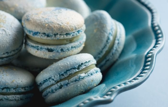 Blue Cotton Candy French Macaron Cookies in a blue bowl on a blue background.