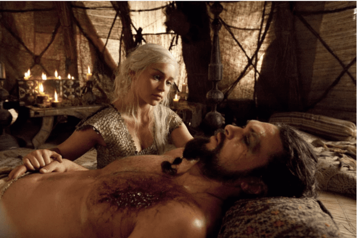 Two Game of Thrones characters--one dead or dying on a bed the other, a woman, looking sad above him.