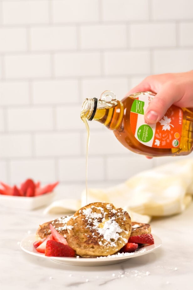 syrup being poured onto french toast on plate