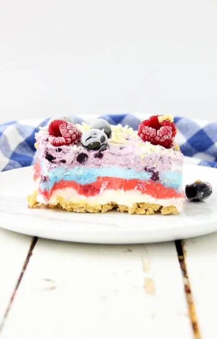 a slice of no bake berry cheesecake on a plate with frozen berries