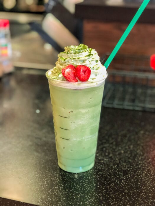 A vanilla bean frappuchino blended with macha powder and topped with two dried straberries is the simple secret menu recipe for this Grinch Frappuchino